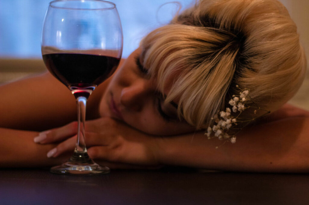 The photo shows a girl drunkenly sleeping next to a glass of wine